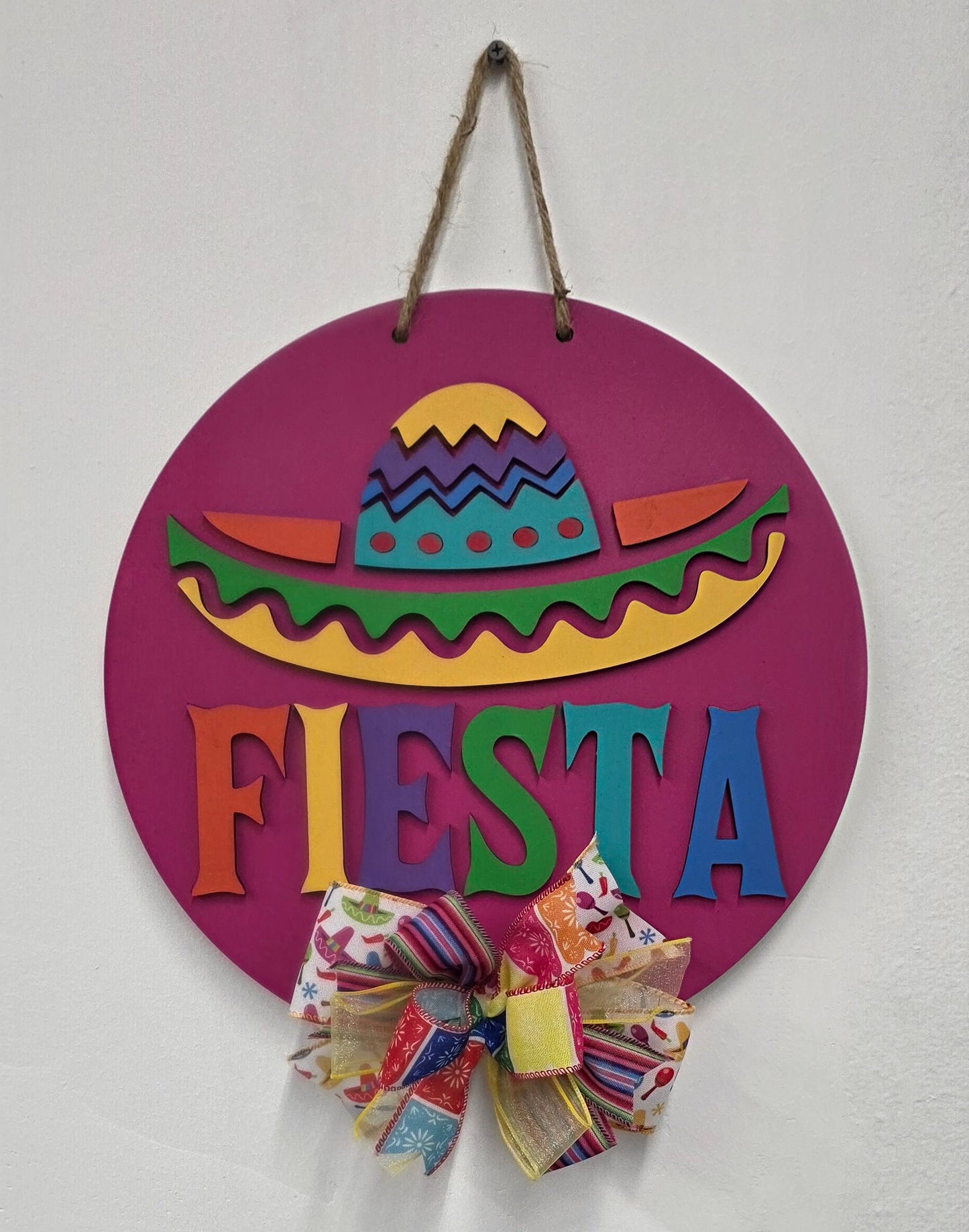 Decorative sign with colorful text and patterns on a white background with a colorful bow