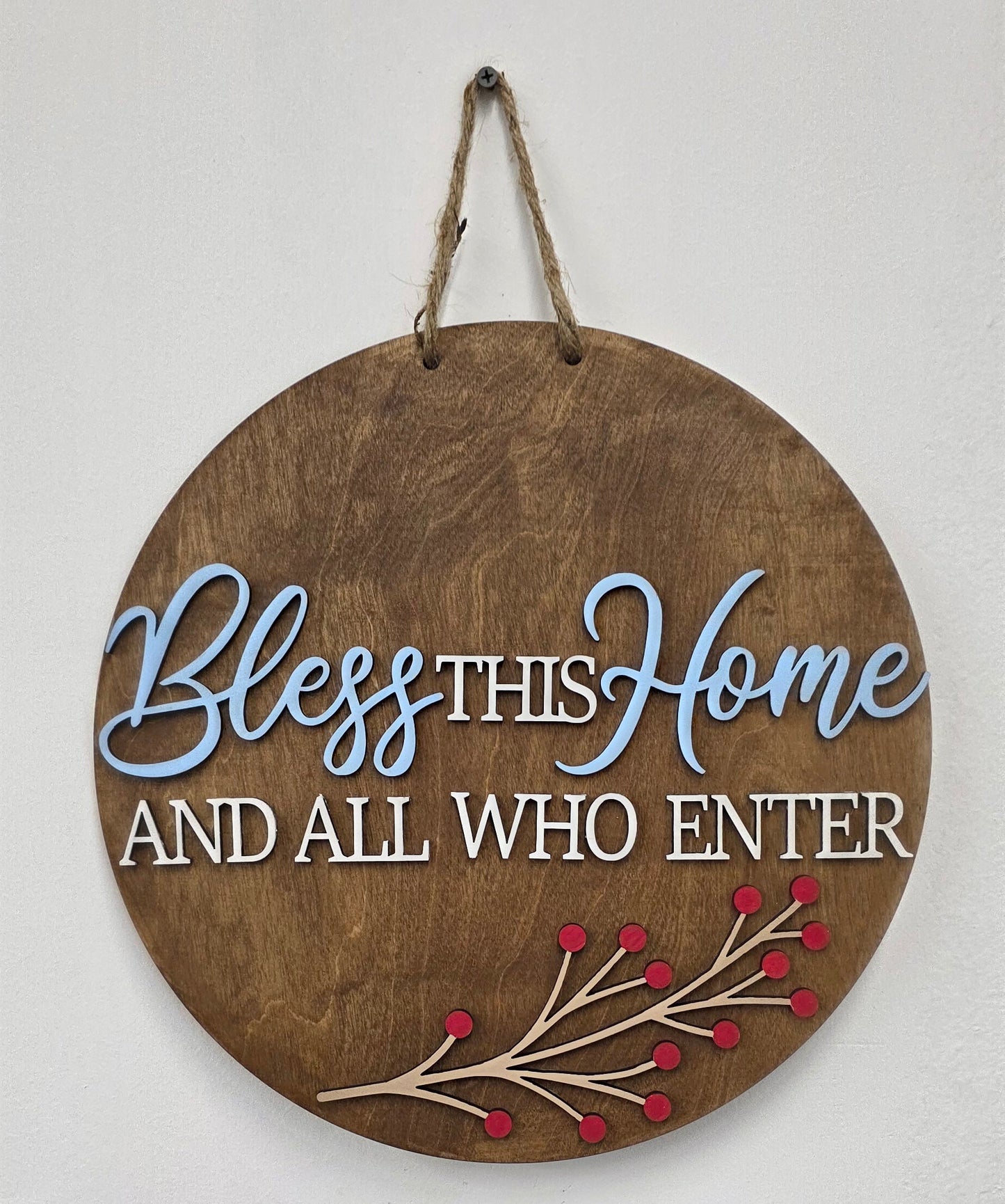 Round wooden sign with decorative text and red berries on a white background