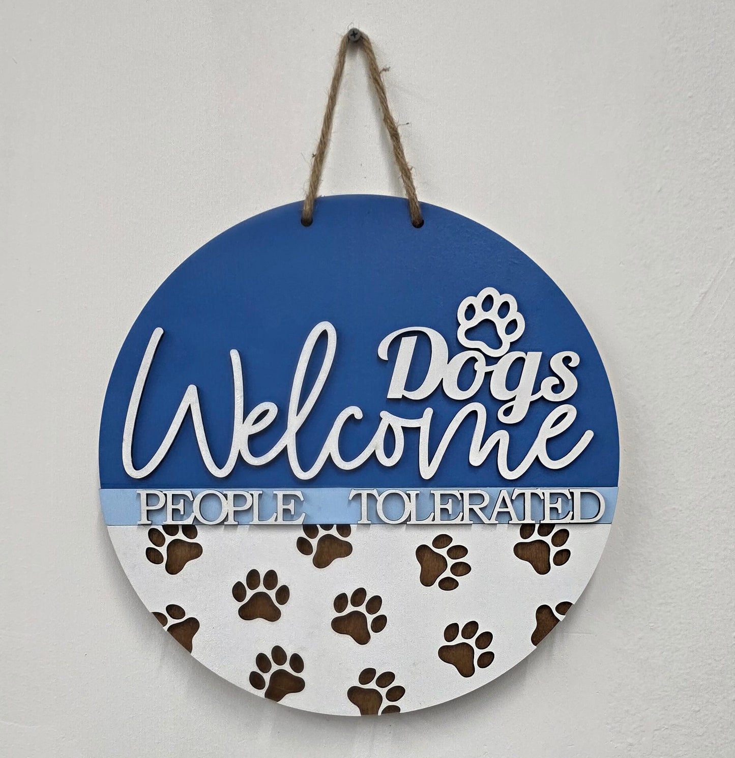 Round sign with 'Welcome Dogs' text and paw prints on a blue background