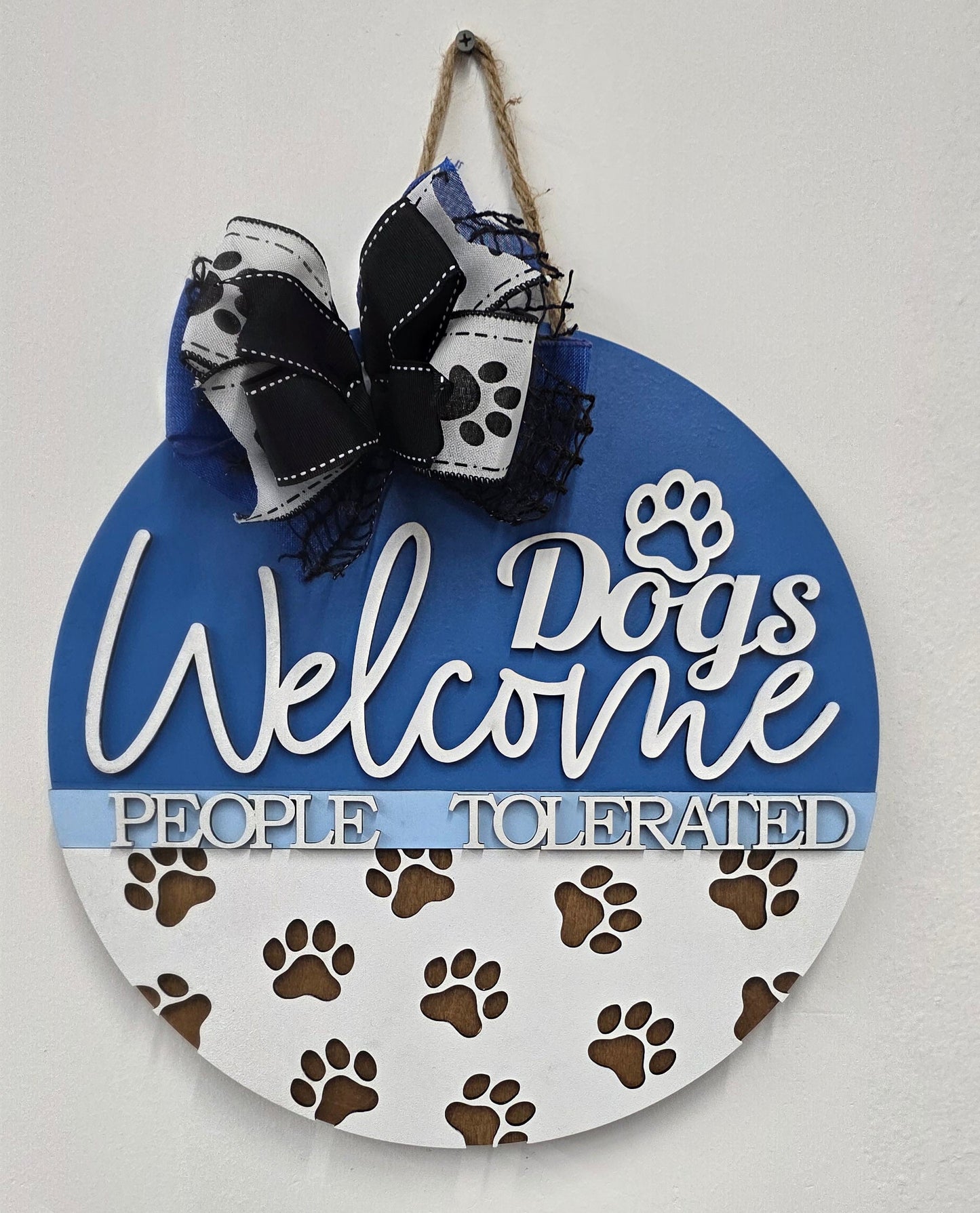 Decorative sign with paw prints and text on a white background with a black and white bow
