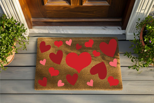 Doormat with red and pink heart patterns on a wooden deck