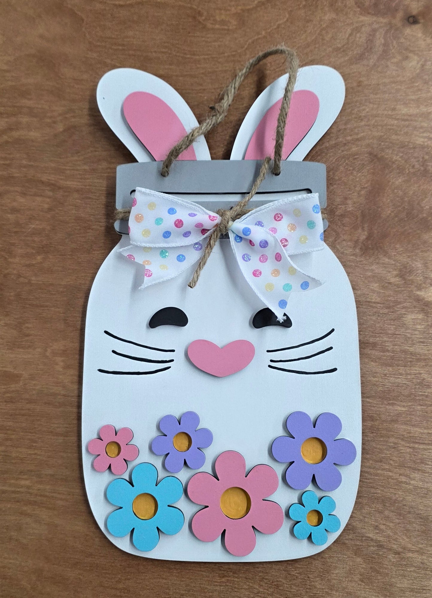 Children's craft project with a bunny template, flowers, and a small dress on a wooden surface.