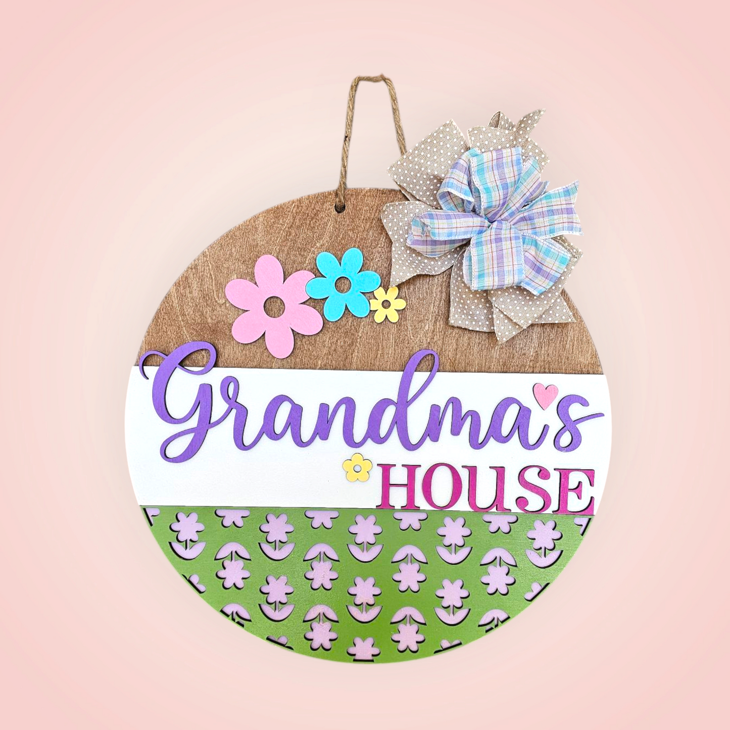 Round sign with the words grandma's house on it and some flowers.