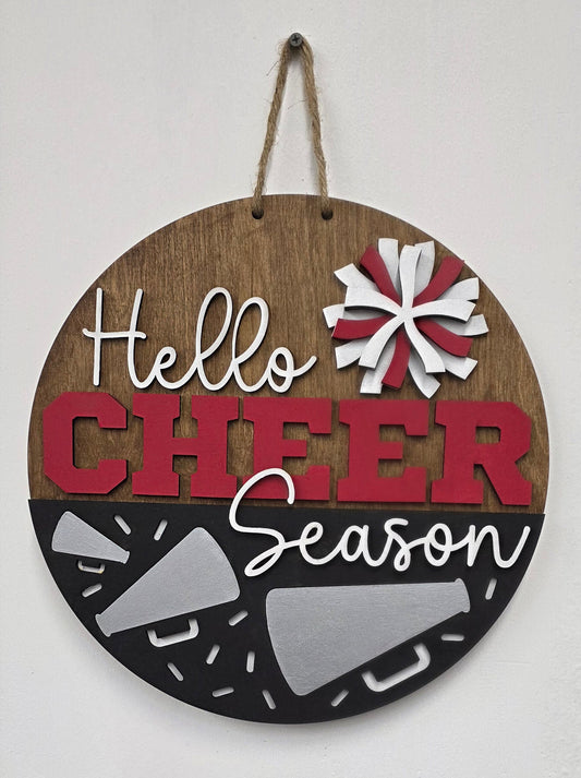 Round wooden sign with 'Hello Cheer Season' text and festive designs on a white background