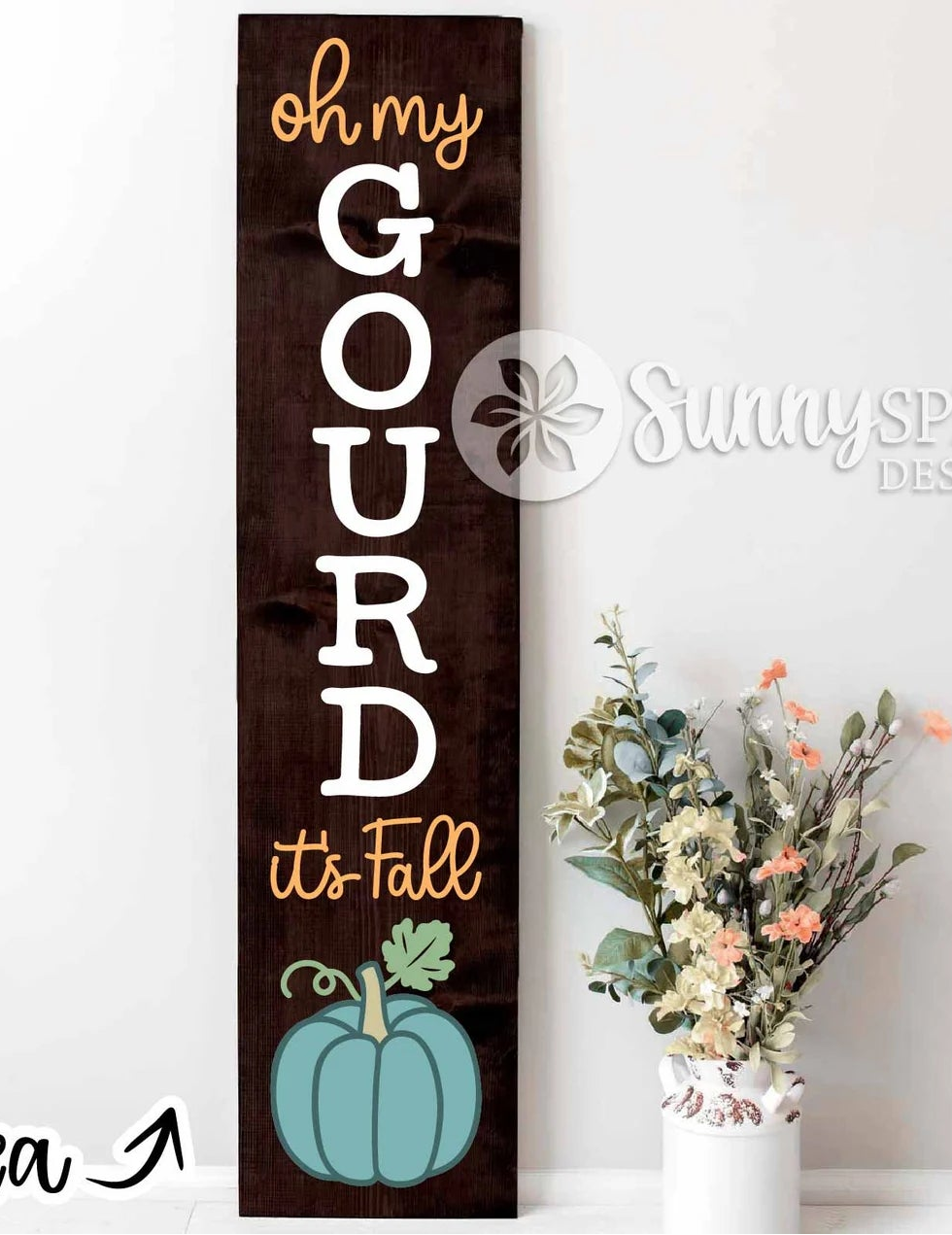 A tall, narrow rustic wooden sign with the phrase 'oh my GOURD it's Fall' in white and gold lettering, featuring a teal pumpkin illustration at the bottom. The sign is displayed next to a white vase with dried flowers against a white wall, with a 'Sunny Sprout Design' watermark and 'Project Idea' text overlay.