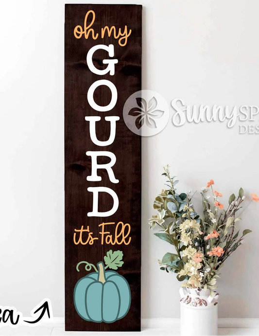 A tall, narrow rustic wooden sign with the phrase 'oh my GOURD it's Fall' in white and gold lettering, featuring a teal pumpkin illustration at the bottom. The sign is displayed next to a white vase with dried flowers against a white wall, with a 'Sunny Sprout Design' watermark and 'Project Idea' text overlay.