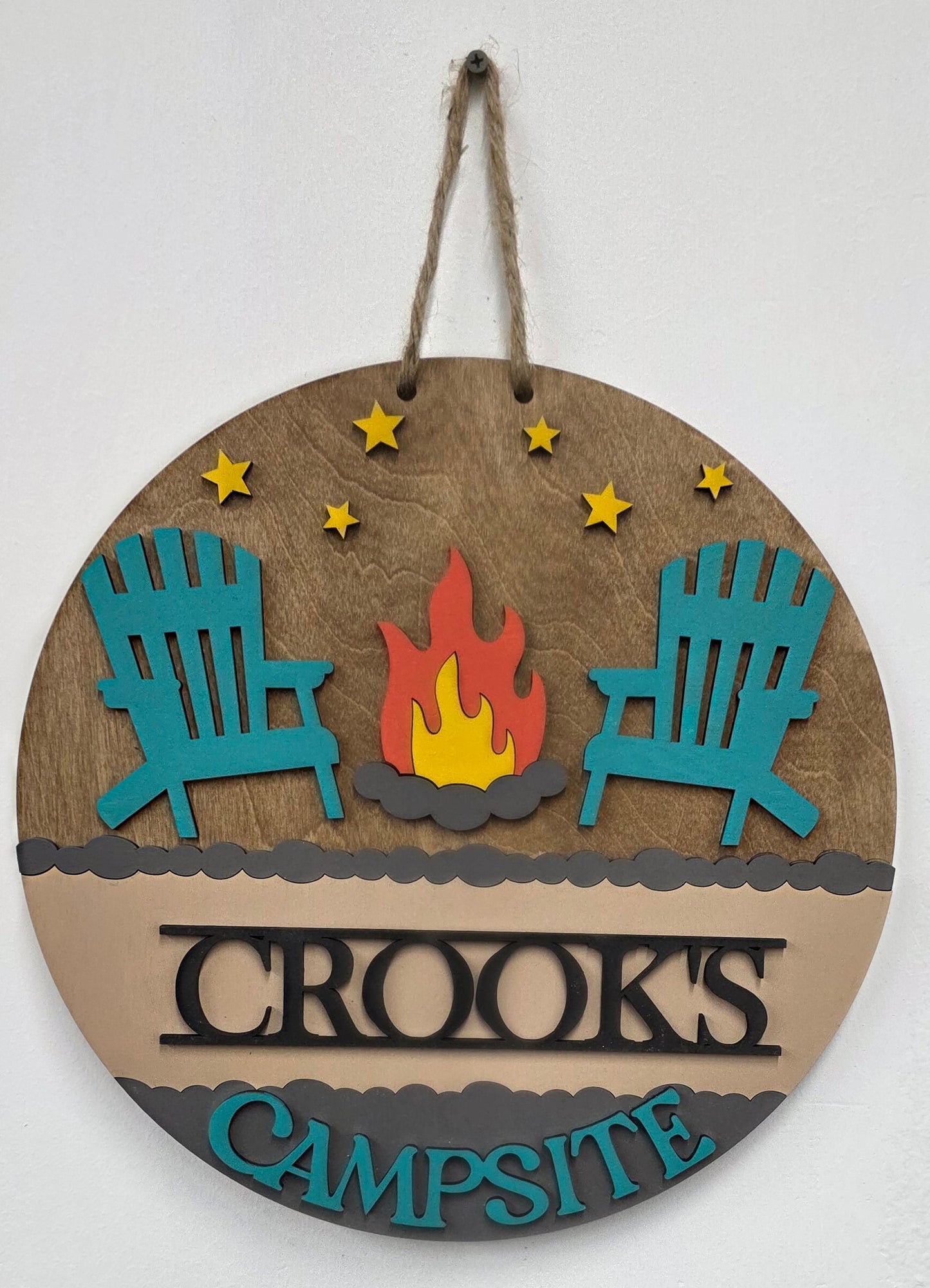 Wooden round sign with 'Crooks Campsite' branding and decorative elements on a white background