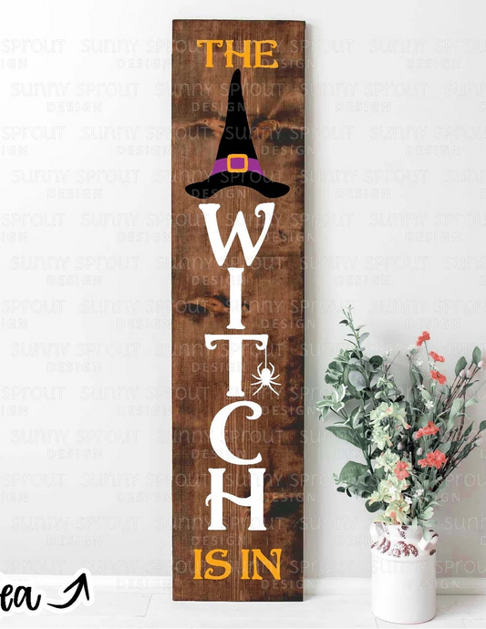 Wooden Halloween sign with 'The Witch is In' text and a vase of flowers on a white background